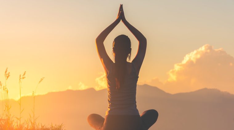 silhouette fitness girl practicing yoga on mountain with sun light