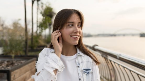 smiley-woman-putting-ear-buds-while-outdoors