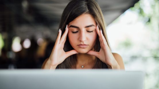Stressed busy tired young girl in working on her report in front of laptop in the summer cafe