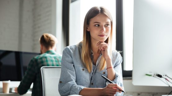 Photo of concentrated young woman work in office using computer and graphic tablet. Looking aside.