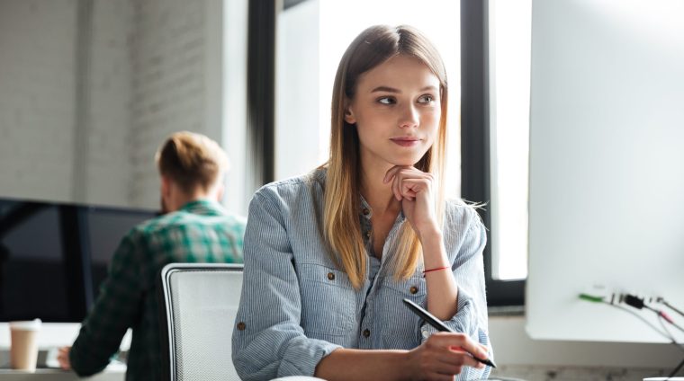 Photo of concentrated young woman work in office using computer and graphic tablet. Looking aside.